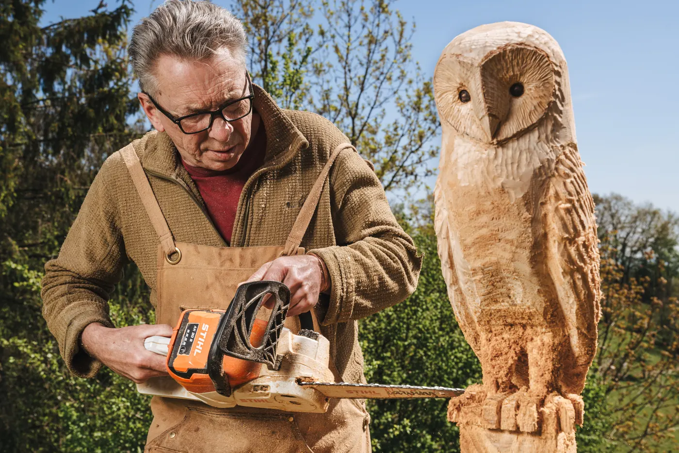 Finishing a hand carved wooden barn owl sculpture outdoors in the Forest of Dean